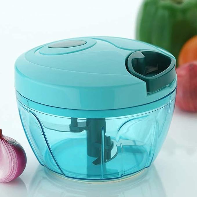 The Vegetable Chopper for Kitchen (Multicolor, 500ml, 3 Blades) is shown on a white surface with an onion, bell pepper, and tomato in the background. Perfect as an onion chopper and vegetable cutter for your kitchen needs.